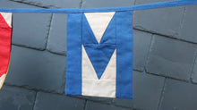 Load image into Gallery viewer, Flag showing the letter M from the Welcome bunting.
