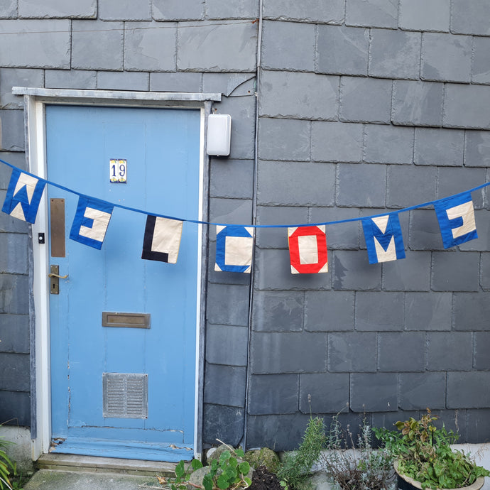 Nautical style bunting which spells out the word Welcome. Double-sided so shows the word welcome on one side and the signal flags that represent the letter on the other side. 272 cms in length.