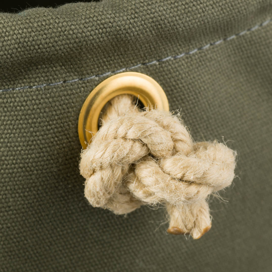 Close up of Cobb Canvas khaki bucket showing the brass eyelet and knotted end of the rope handle