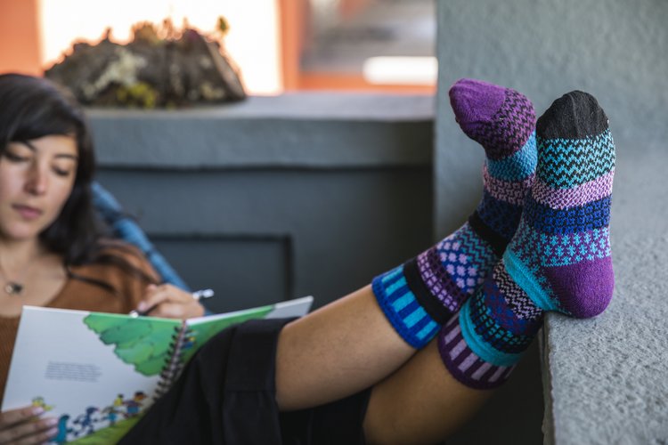 Solmate socks are warm, comfortable and colourful mismatched socks. Made mainly from recycled textiles including 62% recycled cotton. The image shows a design called Raspberry which is in fact a mixture of blues and purples.