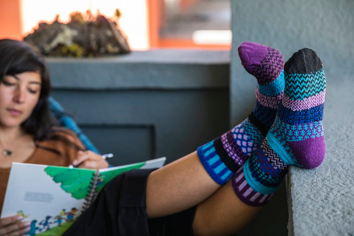 Solmate socks are warm, comfortable and colourful mismatched socks. Made mainly from recycled textiles including 62% recycled cotton. The image shows a design called Raspberry which is in fact a mixture of blues and purples.