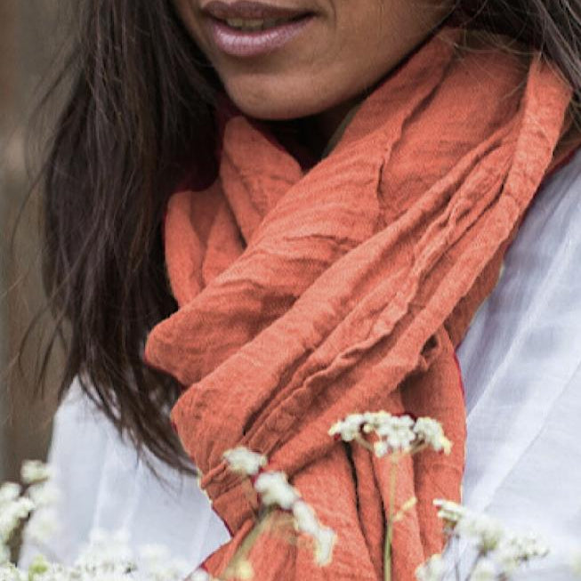 Close up image of a woman wearing a Couleur Chanvre natural hemp scarf in a lovely burnt orange coloiur called Terre de Toscane.