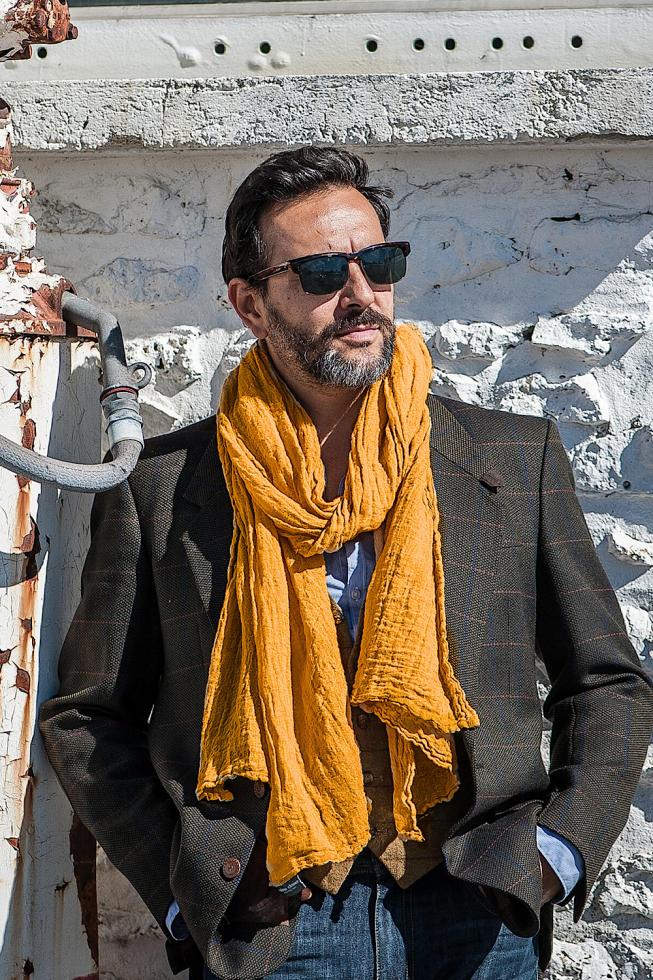 Image of a man wearing a Couleur Chanvre natural hemp scarf in Amber, a bright mustard colour.
