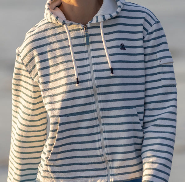 Close up view of Maogad zip up hoodie in cream and provencal blue stripes. Made from organic cotton soft fabric with a textured terry side. Garment features front kangaroo style pockets.